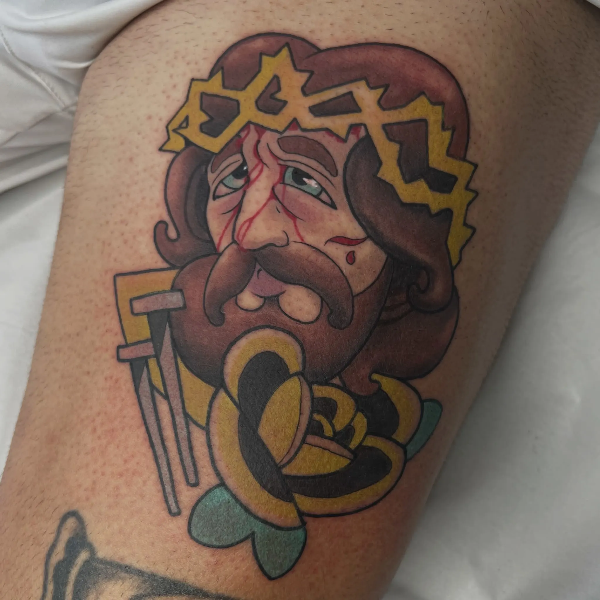 Retrato ilustrativo a color de un Cristo sangrante con nimbo de engranajes amarillos, corona de espinas y lágrima roja, tatuado en el muslo
