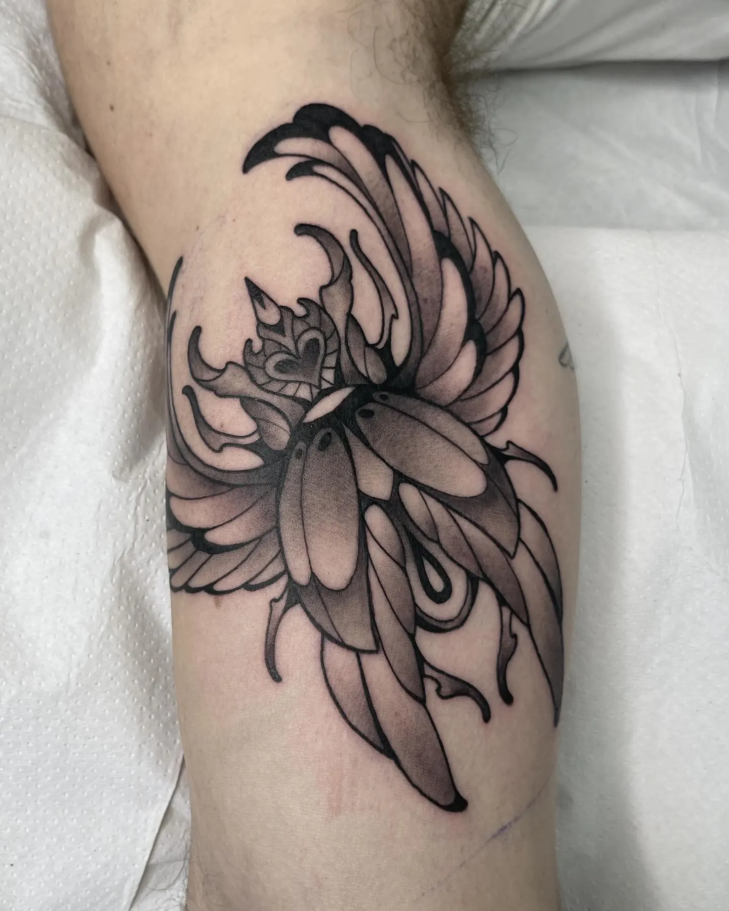Tatuaje blackwork de escarabajo heráldico con claroscuro sobre el muslo