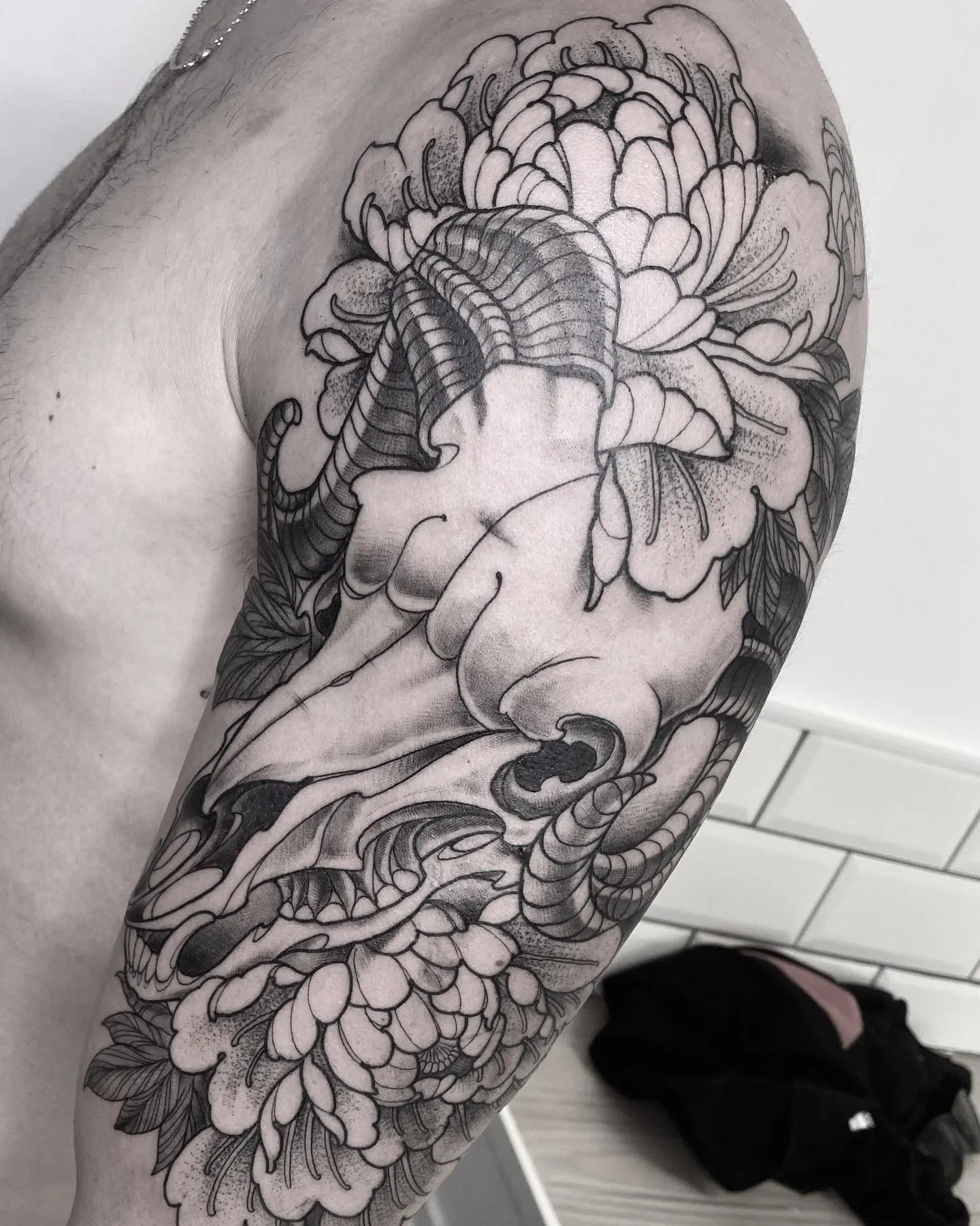 Tatuaje blackwork de peonía japonesa con pétalos en degradado en el brazo