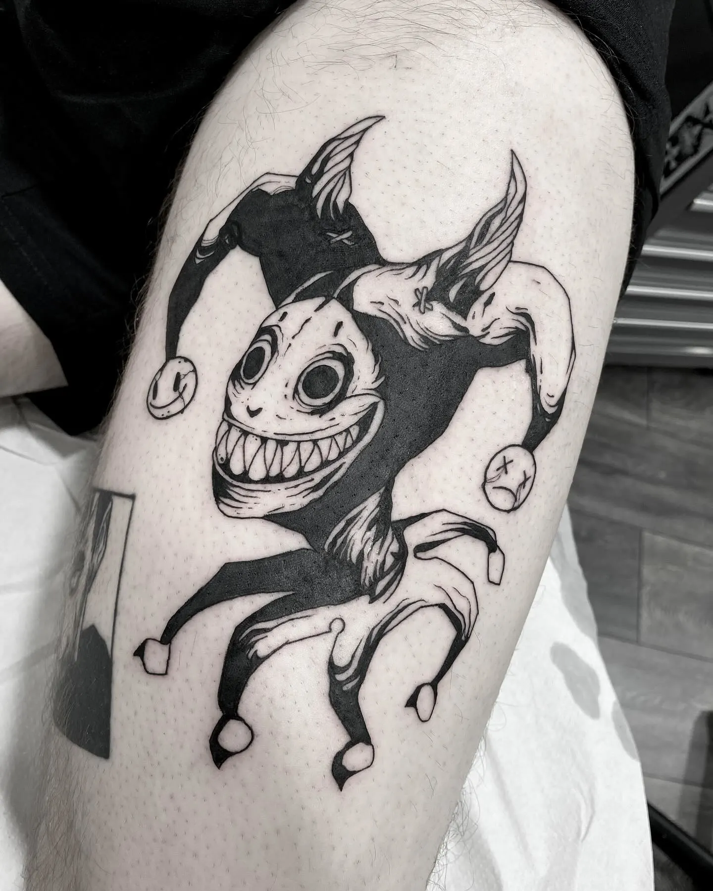 Tatuaje dark art de arlequín con cara agrietada en el antebrazo